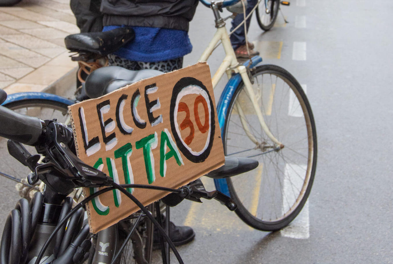 Foto di un ciclista con un cartello con su scritto: Lecce Città 30
